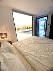 a bedroom with a large bed and a large window at Luxury Farm with Swimming Pool and BBQ in Al Rahba