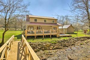 Lyles的住宿－Remote Tennessee Home with Deck, Fireplace, and Creek!，一座黄色的大房子,设有木门廊和一座桥梁