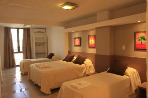 a hotel room with two beds and two tables at HOTEL CONTINENTAL PLAZA in Villa Carlos Paz