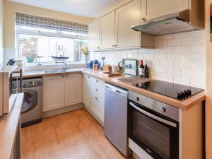 a kitchen with white cabinets and a stove top oven at Elf Cottage in Heacham