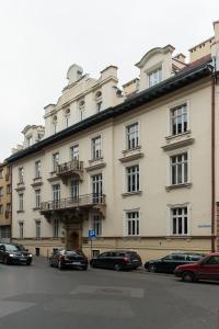 クラクフにあるBeauty of Krakow Apartmentの車が目の前に停まった大きな建物