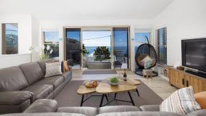ein Wohnzimmer mit einem Sofa und einem TV in der Unterkunft Dutchie's Sand & Sea Beach House - easy walk to the beach in Nelson Bay