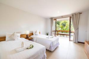 a hotel room with two beds and a balcony at Ban's Diving Resort SHA Extra Plus in Ko Tao