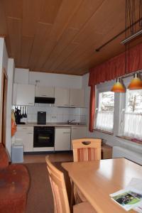 une cuisine avec des armoires blanches et une table avec des chaises dans l'établissement Ferienhaus Haus am Medebach, à Olsberg