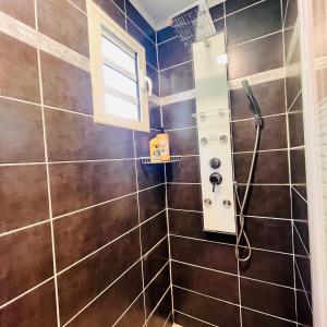 y baño con ducha de azulejos marrones. en Ti'Laos, en Cilaos