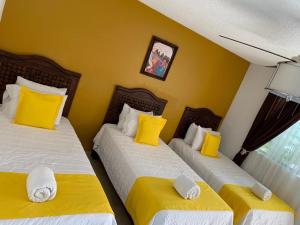 a bedroom with two beds with yellow and white pillows at Hotel Muñoz de Luna in Huajuapan de León