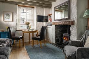 - un salon avec une table et une cheminée dans l'établissement Gull Cottage, à Conwy