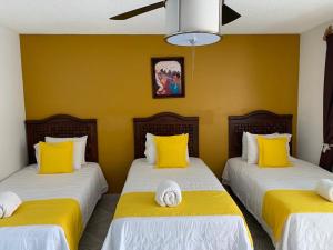 two beds in a room with yellow walls at Hotel Muñoz de Luna in Huajuapan de León