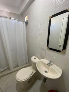 a white bathroom with a toilet and a sink at Hotel Aventura Riohacha in Ríohacha