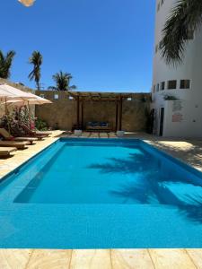 a large blue swimming pool with chairs and a building at Hotel Estrella de Mar in Zipolite