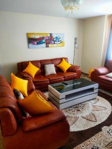 una sala de estar con un sofá de cuero marrón con almohadas amarillas en Inviting 3-Bed Apartment in Nairobi en Nairobi