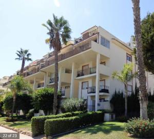 um grande edifício branco com palmeiras e arbustos em Mijas Golf penthouse em Santa Fe de los Boliches