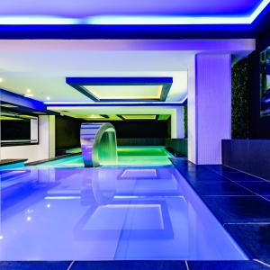 a swimming pool in a building with blue lights at Kolejarz Best For You SPA in Ustroń