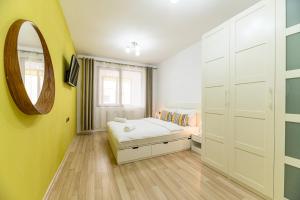 una camera da letto con un letto e uno specchio a parete di JAD - Comfortable 3 Rooms Family Apartments Coresi ISARAN a Braşov