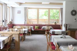 ein Restaurant mit Tischen, Stühlen und Fenstern in der Unterkunft Hotel Landle in Galtür