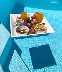 a plate of food on a table with glasses of juice at CASA FERDI 1, logement entier avec piscine privée in Le Marin