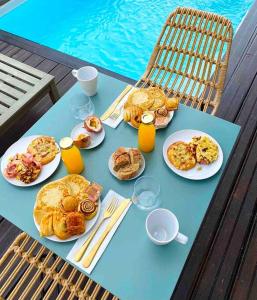 una mesa con comida para el desayuno y bebidas en ella en CASA FERDI 1, logement entier avec piscine privée, en Le Marin