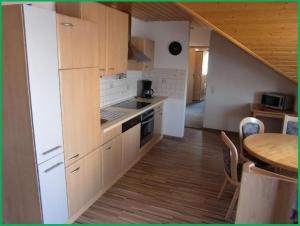 a kitchen with white cabinets and a wooden floor at Haus-Fechtig-Wohnung-Typ-C in Bonndorf im Schwarzwald
