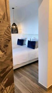 un letto bianco con cuscini blu in una stanza di CASA FERDI 1, logement entier avec piscine privée a Le Marin