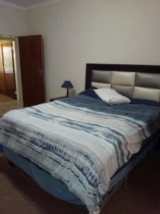 een slaapkamer met een groot bed met blauwe en witte lakens bij Butterfly Guest House in Lekkerrus