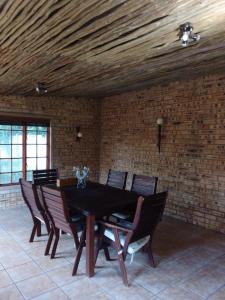 een eettafel met stoelen en een bakstenen muur bij Butterfly Guest House in Lekkerrus