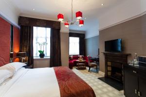 um quarto com uma cama, uma lareira e uma televisão em The Capital Hotel, Apartments & Townhouse em Londres