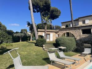 a yard with chairs and a house with palm trees at Magnifique Villa de prestige Antibes/Juan-les-Pins in Antibes