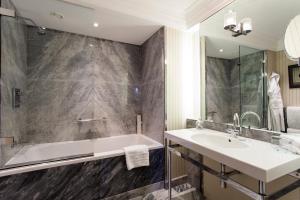 a bathroom with a sink and a tub and a mirror at The Capital Hotel, Apartments & Townhouse in London