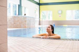 Eine Frau, die im Schwimmbad liegt. in der Unterkunft Kents Hill Park Training & Conference Centre in Milton Keynes