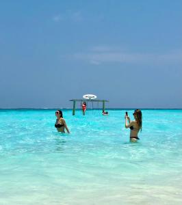 three women standing in the water at the beach at Aqua Sunset in Gulhi