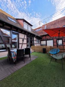 patio con tavolo, sedie e ombrellone di L'Appart avec terrasse - centre historique a Barr