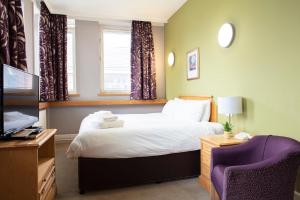 1 dormitorio con 1 cama, TV y silla en Kents Hill Park Training & Conference Centre en Milton Keynes