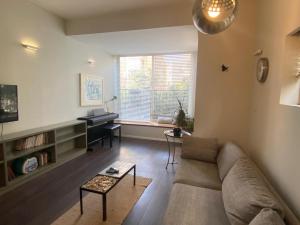 een woonkamer met een bank en een piano bij Tender grey by HolyGuest in Tel Aviv