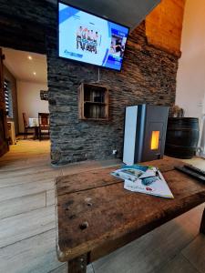 a wooden table with a tv on a stone wall at La Ptit Marie in Houffalize