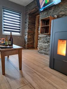 a living room with a fireplace and a table and a tv at La Ptit Marie in Houffalize