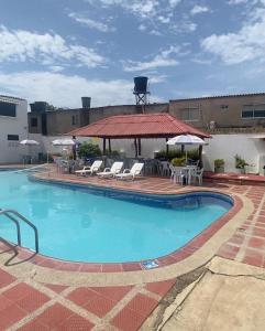 里奧阿查的住宿－Hotel la Sierra Riohacha II，一个带椅子和凉亭的大型游泳池