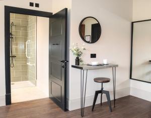 a bathroom with a shower and a table and a mirror at Vive Hotel in Hastings
