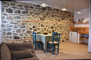 cocina con mesa, sillas y pared de piedra en The apricot tree studio, en Samotracia