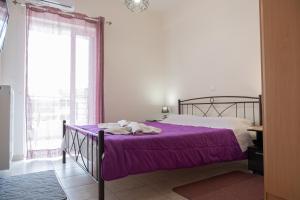 Un dormitorio con una cama con sábanas moradas y una ventana. en Despoina's Lovely Apartment, en Nauplia