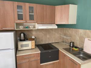 a kitchen with wooden cabinets and a sink and a microwave at Comfort Apartment in Pomorie