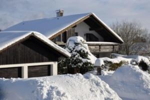 een huis bedekt met sneeuw met een berg sneeuw bij Harzhaus Rauch in Braunlage