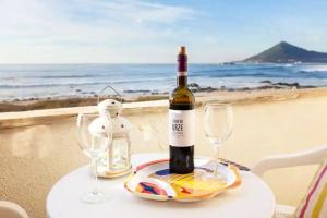 una bottiglia di vino e due bicchieri su un tavolo vicino alla spiaggia di One bedroom house with sea view enclosed garden and wifi at Moledo a Moledo