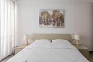 1 dormitorio con 1 cama blanca y 2 lámparas en Gospa 58 - 1 bedroom apt en Birżebbuġa