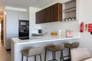 Eine Küche mit einer Theke und zwei Barhockern. in der Unterkunft Gospa 58 - 1 bedroom apt in Birżebbuġa
