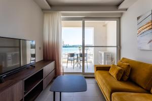 a living room with a couch and a television at Gospa 58 - 1 bedroom apt in Birżebbuġa