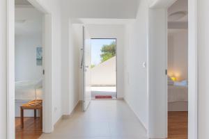 een witte hal met een deur naar een slaapkamer bij Apartment URSA in Podgora