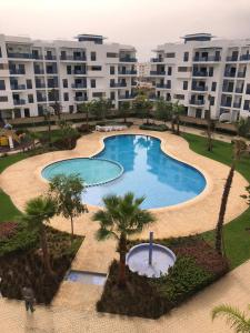 - une vue sur la piscine bordée de palmiers et de bâtiments dans l'établissement Costa Mar , avenue Miramar, à Martil