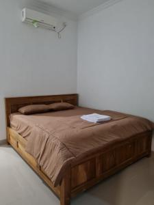 Cama de madera en habitación con pared blanca en Nexdeco House Homestay Syariah Solo, en Solo