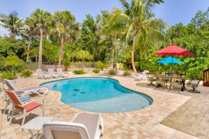 a swimming pool with chairs and a table and umbrella at Baybarlyn home in Captiva