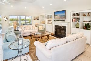 a living room with white furniture and a fireplace at Baywatch Casa home in Captiva